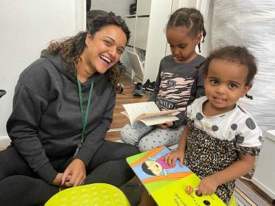 Volunteer with two children reading books