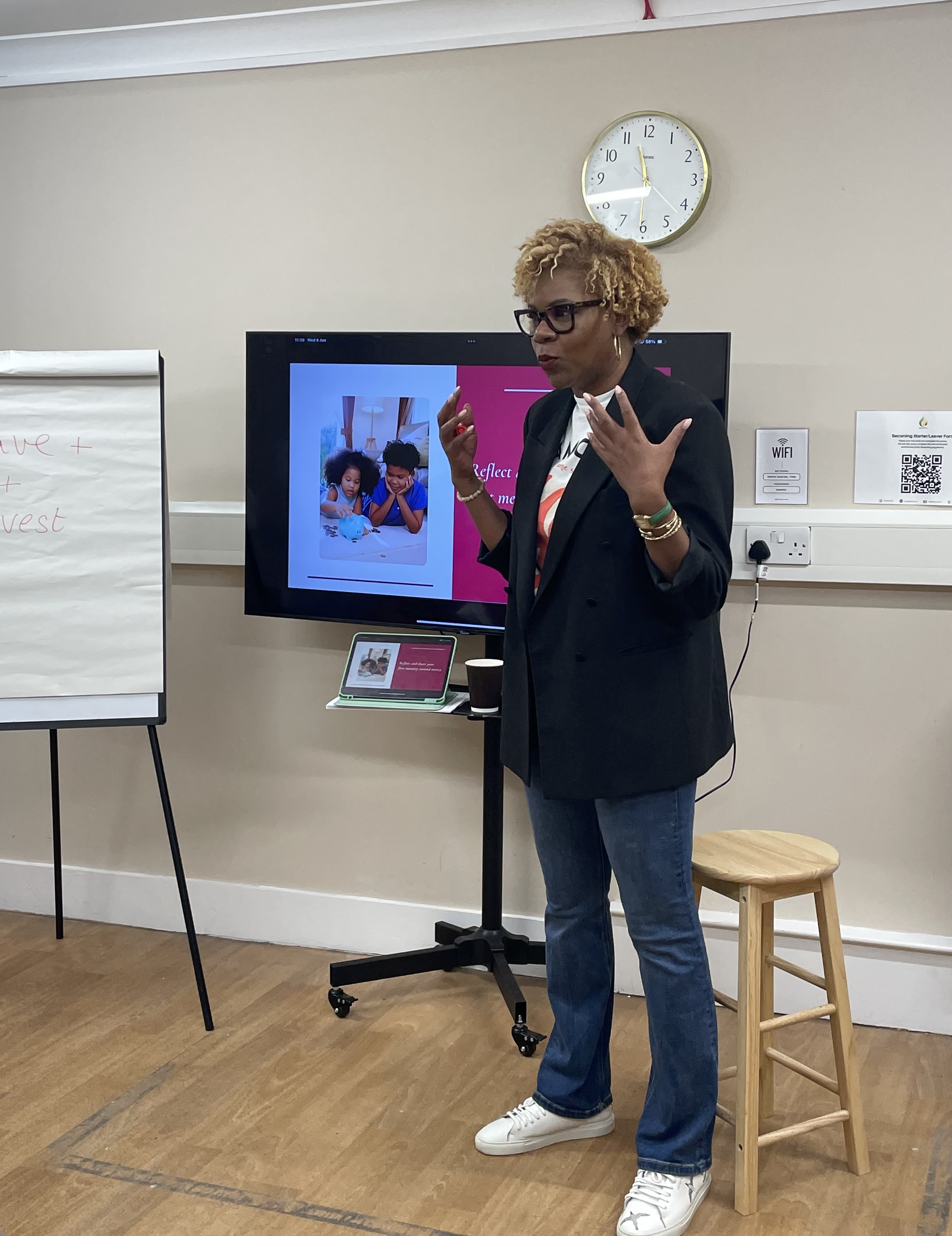 a smartly dressed woman giving a presentation in front of a screen